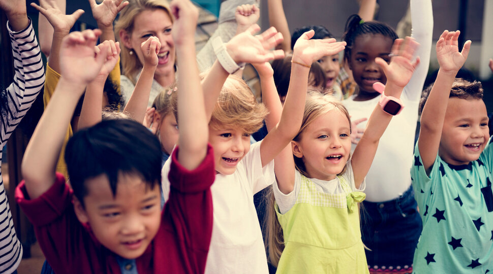 Viele Kinder, die ihre Arme in die Höhe halten und jubeln