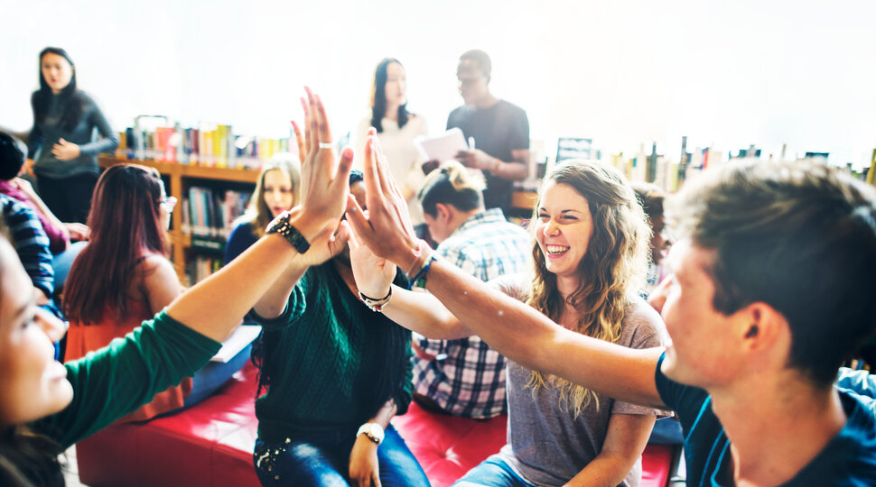 Jugendliche sitzen zusammen, lachen und klatschen ab