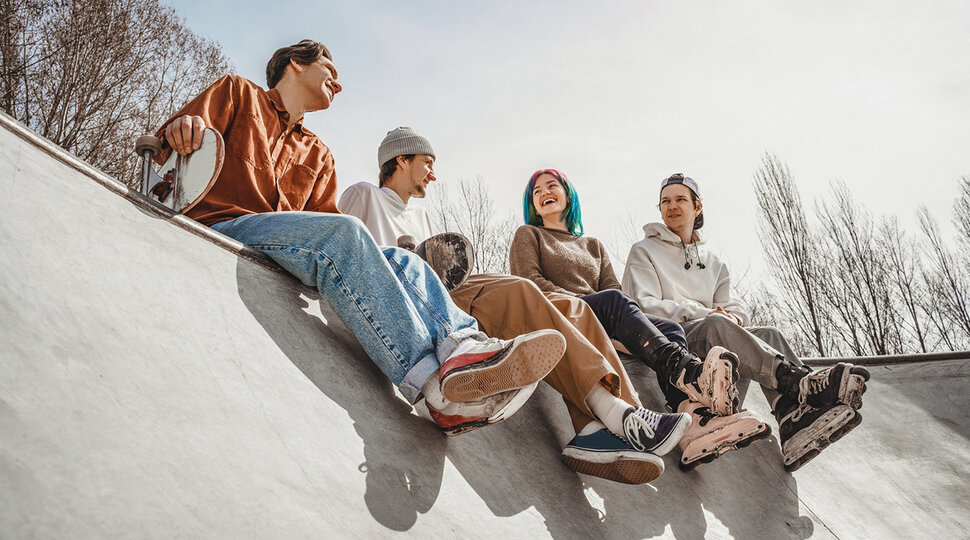 Vier Jugendliche sitzen auf einer Skaterampe