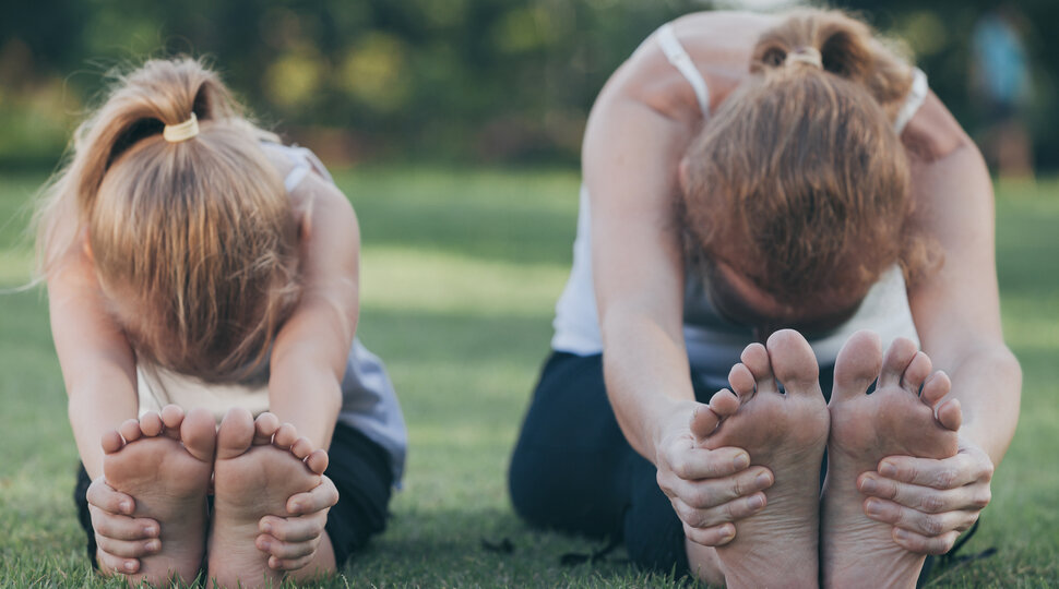 Zwei Mädchen beim Yoga auf einer Wiese