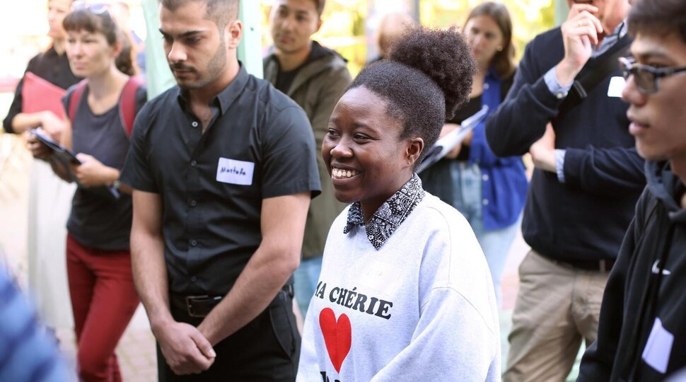 Eine junge Frau mit Migrationshintergrund ist bei einer Veranstaltung und lächelt