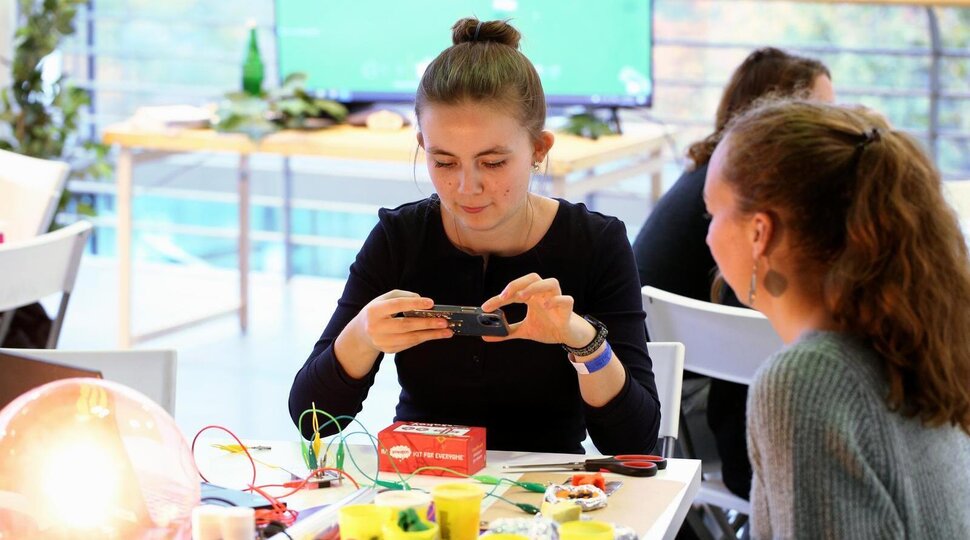 Zwei Festivalbesucherinnen sitzen an einem Tisch und machen ein Foto