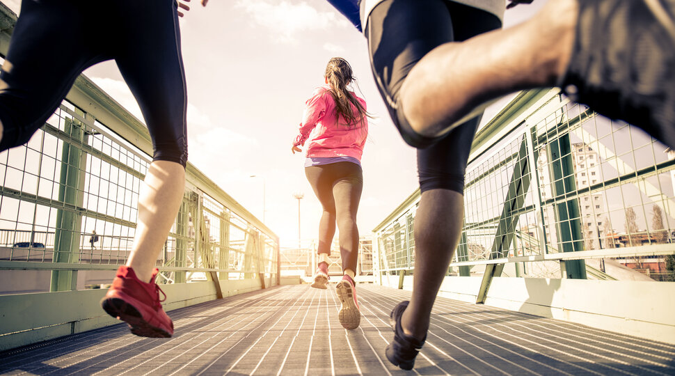 Junge Menschen joggen über eine Brücke