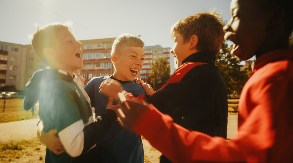 Multiethnische Jungs spielen Fußball draußen im städtischen Hinterhof