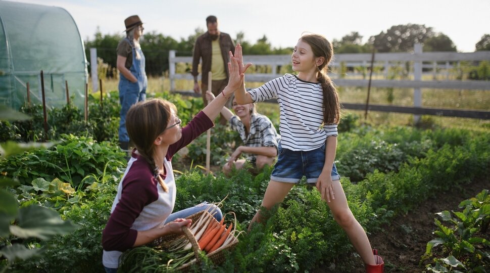 Ein Mädchen und eine Erwachsene klatschen in einem Gemeinschaftsgarten ab