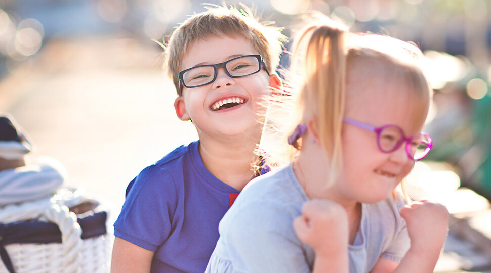 Ein Mädchen und ein Junge mit Down-Syndrom lachen