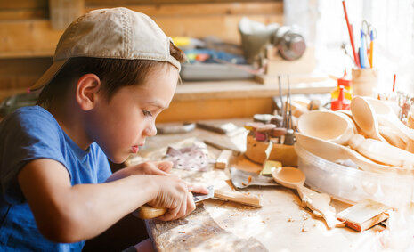 Ein Junge bastelt mit Holz in einer Werkstatt