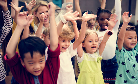 Viele Kinder, die ihre Arme in die Höhe halten und jubeln