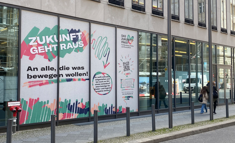 Ein Bild von der Fensterfassade des BMFSFJ in Berlin, auf die Werbung für das Zukunftspaket geklebt wurde.