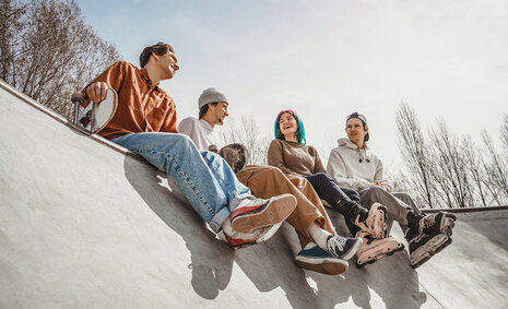 Vier Jugendliche sitzen auf einer Skaterampe