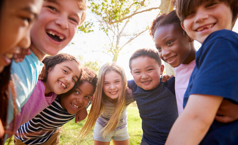 8 Kinder stehen in einem Halbkreis und lachen in die Kamera