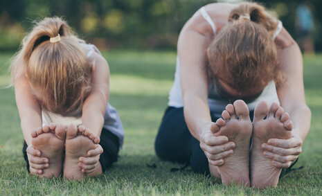 Zwei Mädchen beim Yoga auf einer Wiese