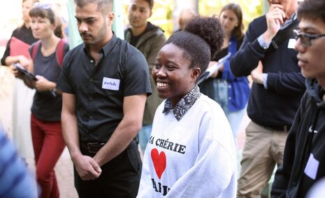 Eine junge Frau mit Migrationshintergrund ist bei einer Veranstaltung und lächelt
