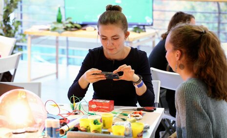 Zwei Festivalbesucherinnen sitzen an einem Tisch und machen ein Foto