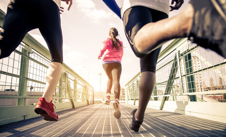 Junge Menschen joggen über eine Brücke