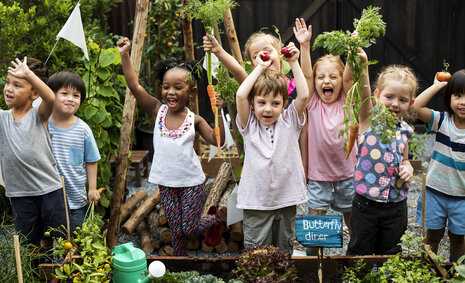 Kinder ernten Gemüse und springen vor Freude in die Luft